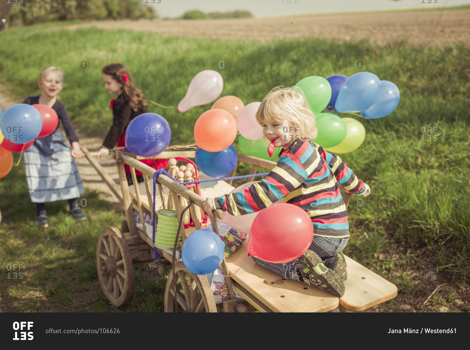 Children on the move with wooden trolley and balloons