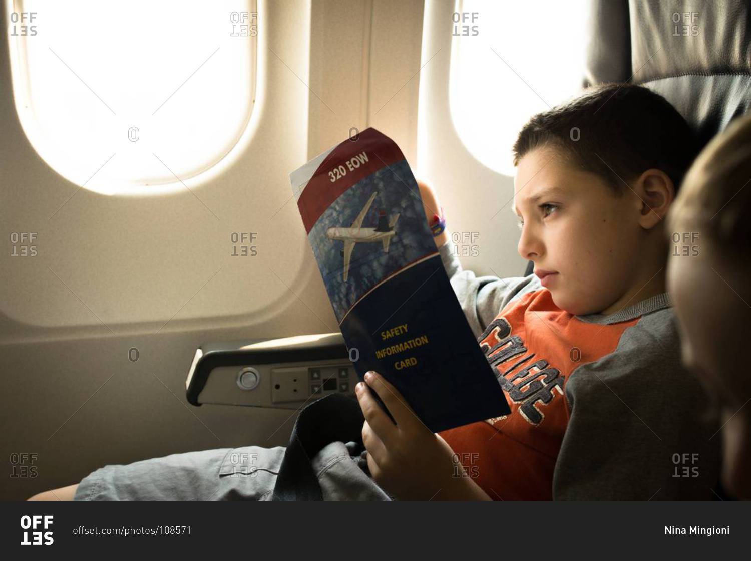 Boy reading the safety information on an airplane