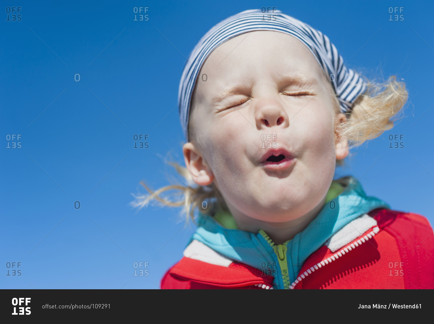 Boy pulling faces under blue sky