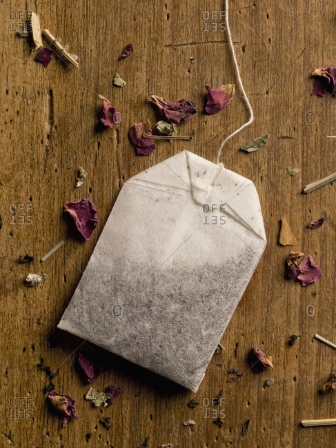 Herbal teabag and petals on wooden table