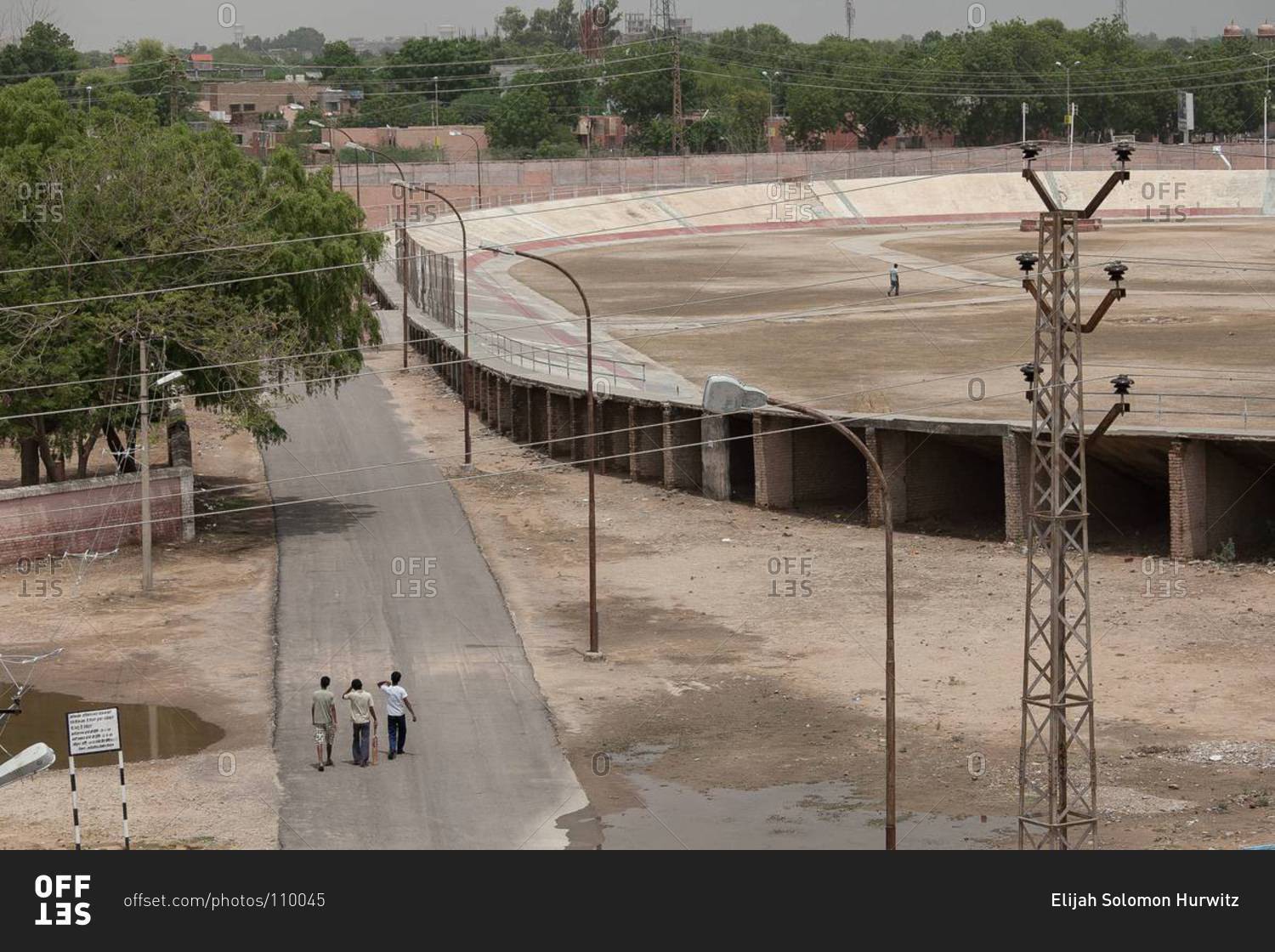 Young men walk to an empty stadium to play cricket in Bikaner, India