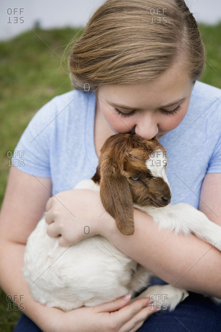 A girl cuddling a baby goat