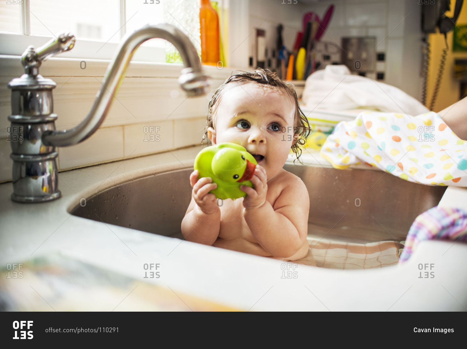 Baby girl playing with a duck toy in a sink