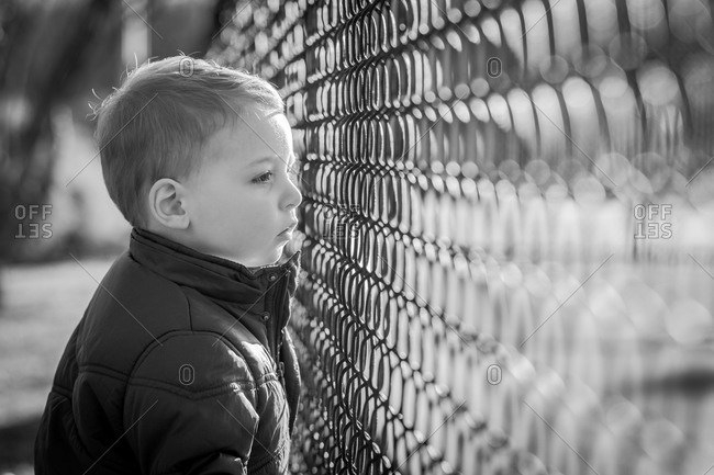 Boy looking through a wire fence