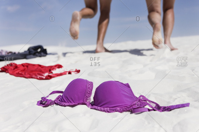 Couple running away on sand leaving clothes behind in White Sands, New Mexico, USA