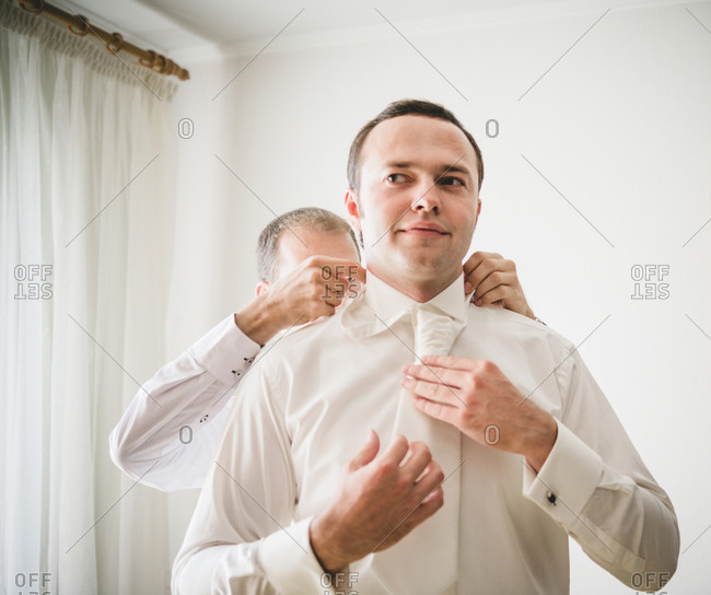 Groomsman fixing the groom's collar