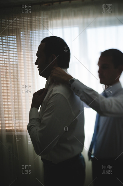 Groomsman adjusting the groom's collar