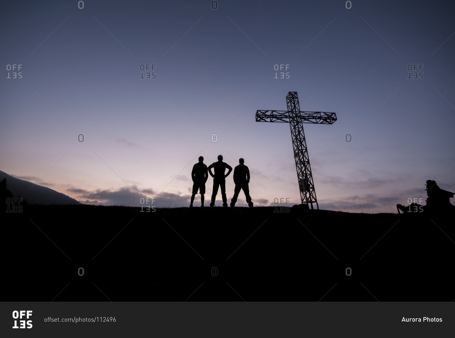 Silhouette of three boys standing near a cross at the summit of a mountain, Ossola, Italy