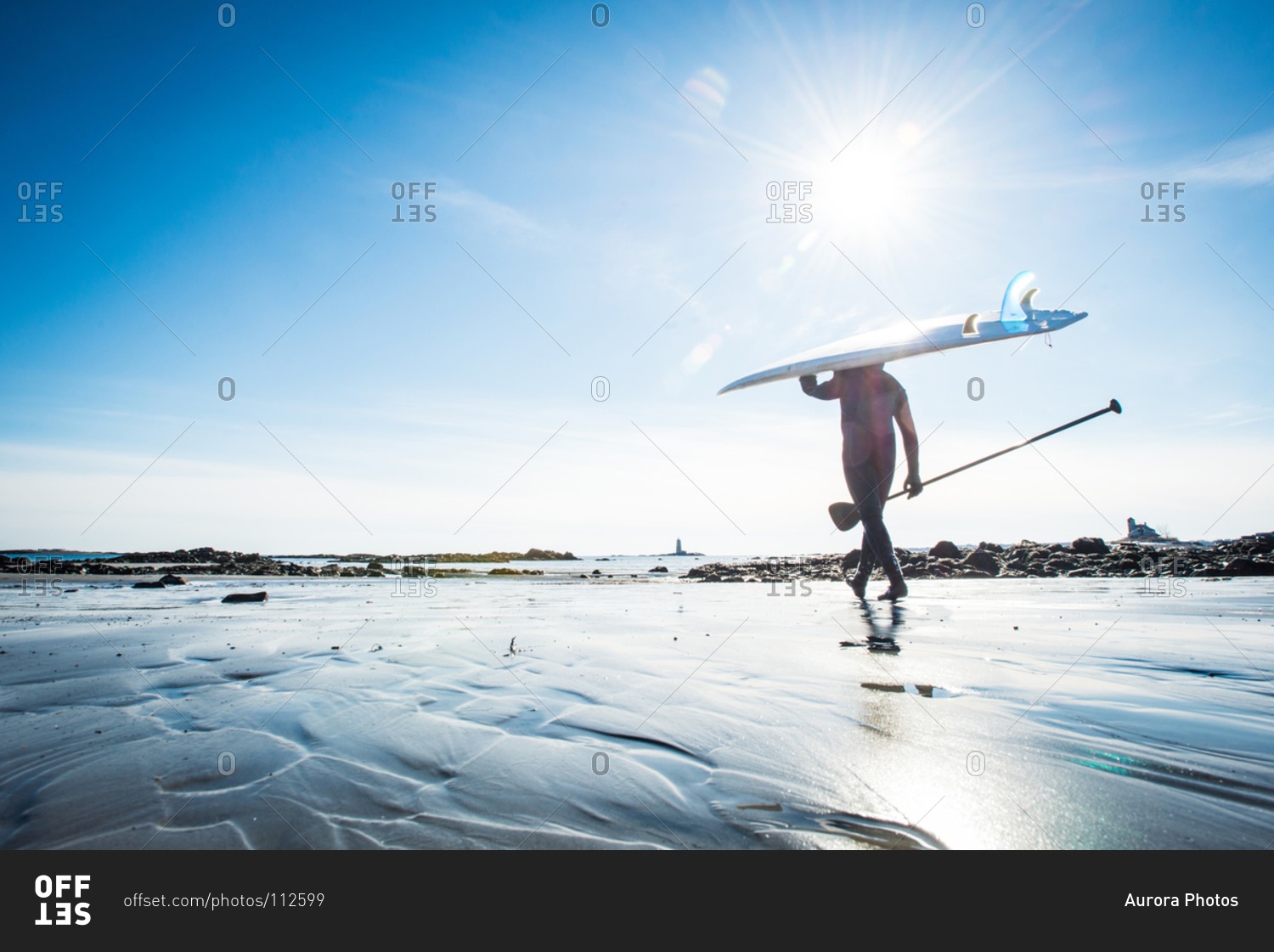 Wide angle view of a man in winter going stand up paddle surfing in Kittery, Maine