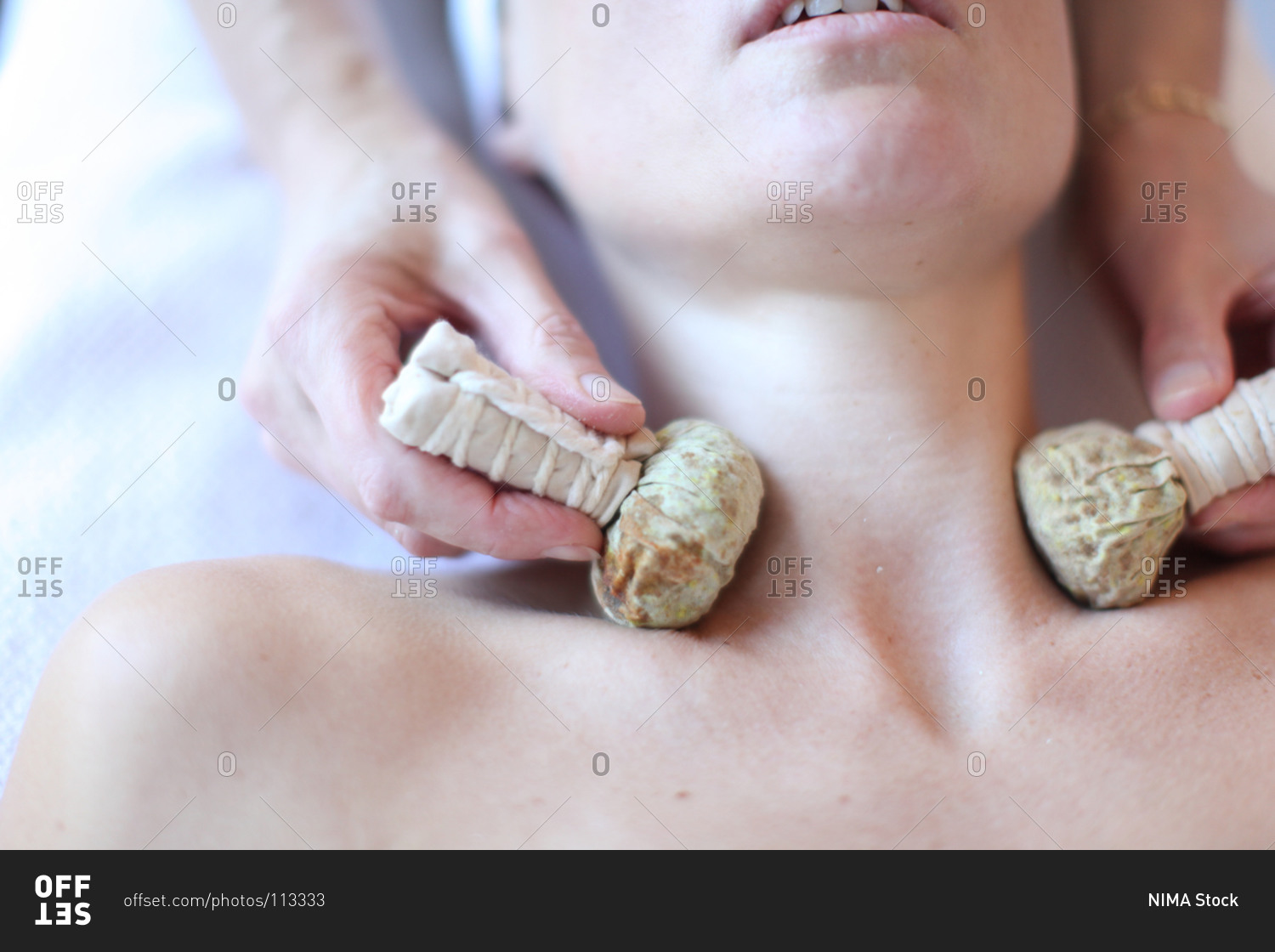 Young woman receiving neck massage with herbal balls