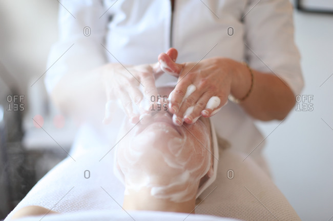 Beauty therapist gives facial cleansing treatment with facial antiseptic foam