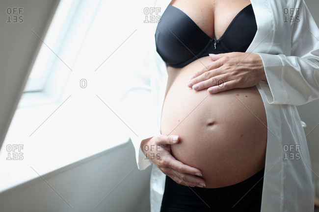 Woman with a Big Bare Tummy is Sitting on a Bed in Her Underwear with a  Bare Stomach. a Pregnant Lady and Her Husband Hold Their Stock Photo -  Image of contemplation