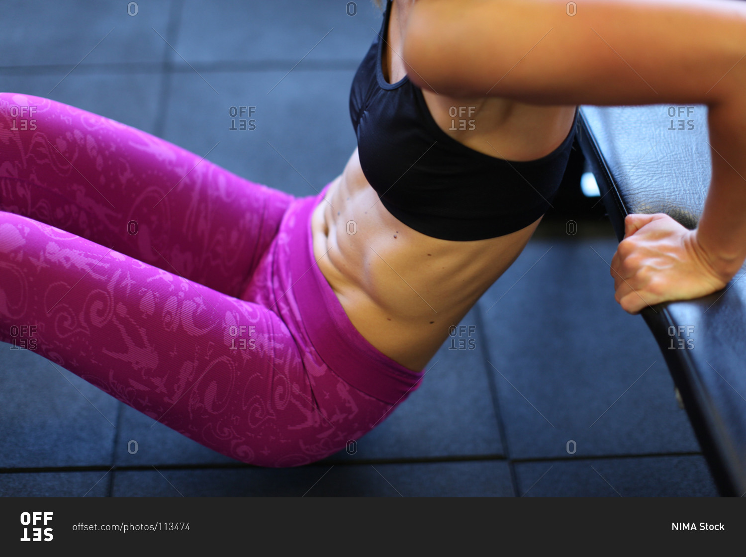 Midsection of woman doing triceps dips health club