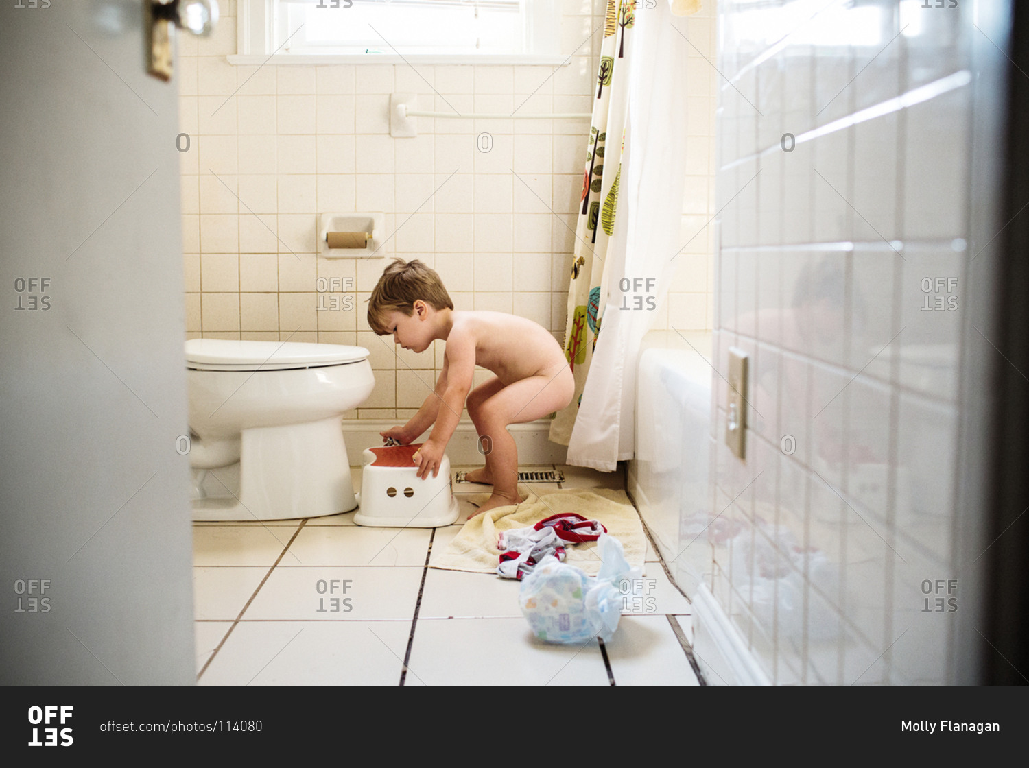Full length of a little boy placing anti-slip foot stool by a flush toilet