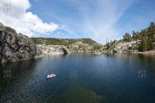 Woman floating on an inflatable raft on an alpine lake in Desolation Wilderness, California