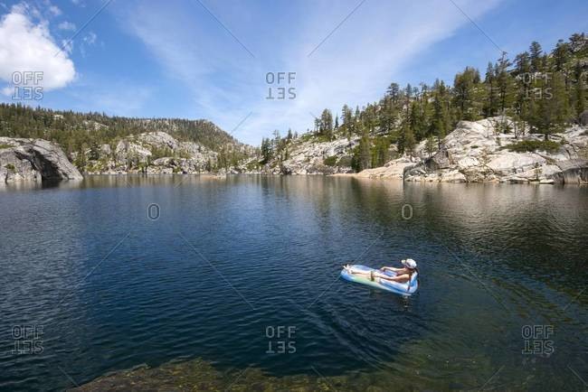 Woman floating on an inflatable raft on an alpine lake in Desolation Wilderness, California