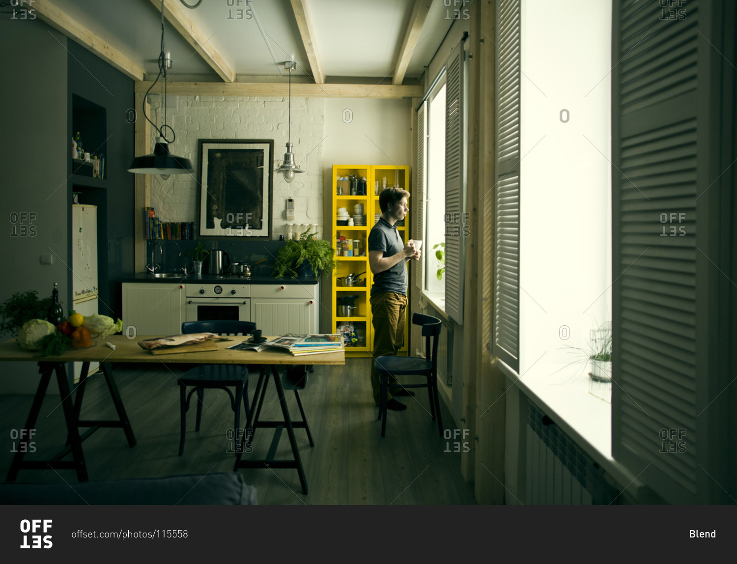 Man looking out kitchen window stock photo - OFFSET