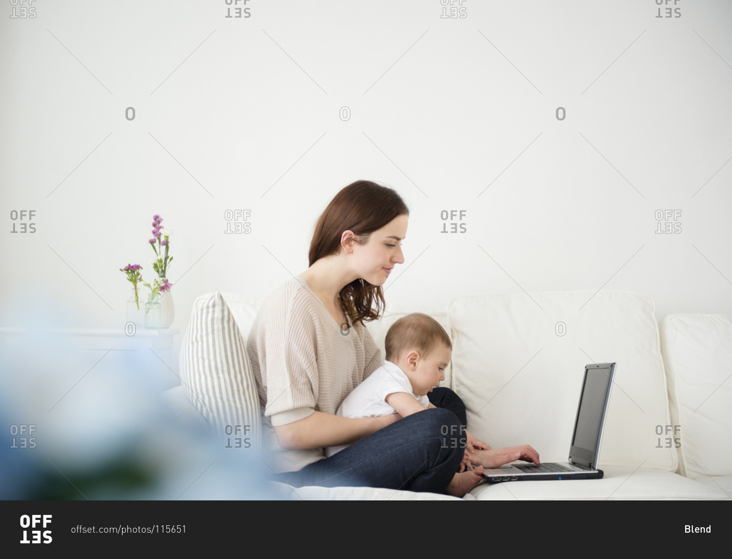 Mother and baby using laptop on sofa