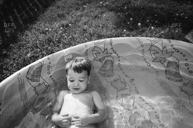 Little boy lying in a kiddie pool