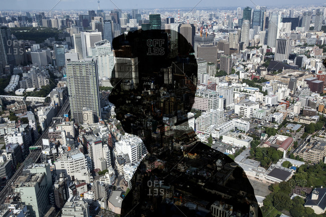 Man looking through window at cityscape stock photo - OFFSET