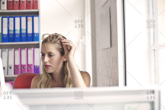 Blonde woman touching her glasses in an office