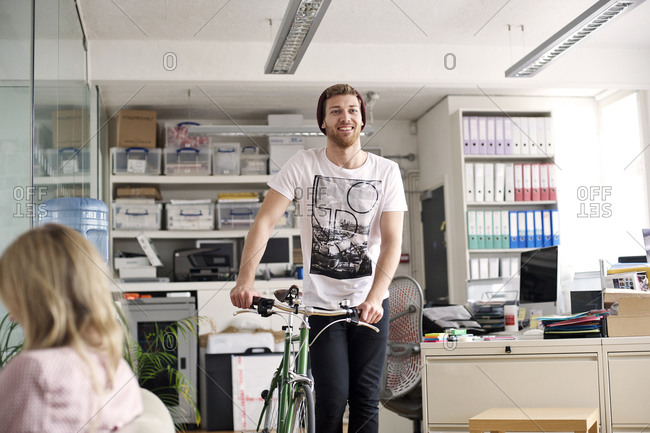 Young man with a bicycle in an office