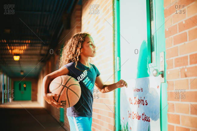 Young girl holding a basketball in a school