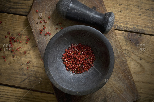 Mortar with dried red peppercorns on wood, elevated view