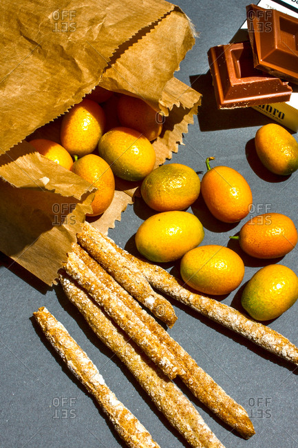 Toppled bag of breadsticks and kumquat