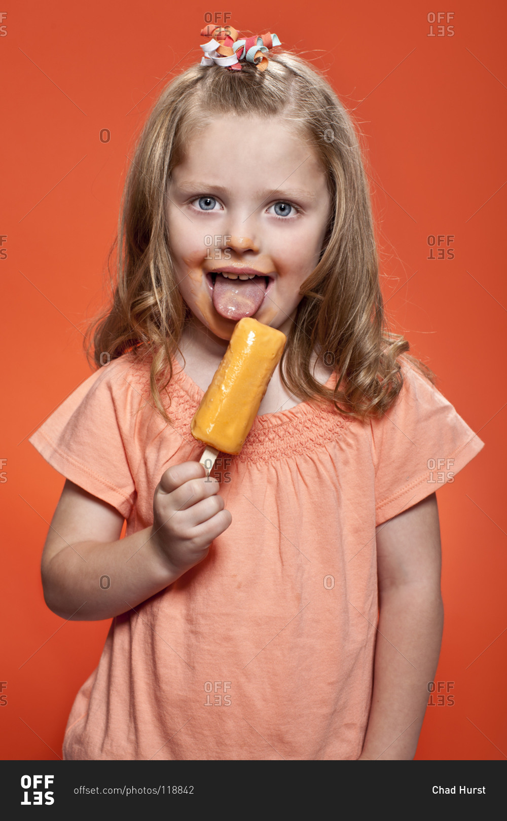 Little, long haired girl eating fruity ice cream bar