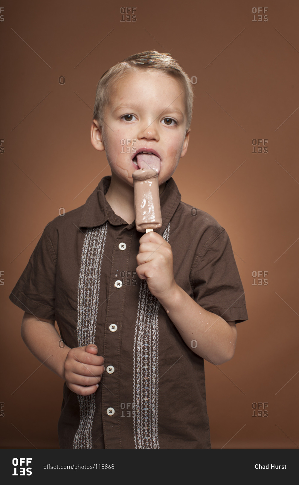 Boy licking a chocolate ice cream bar