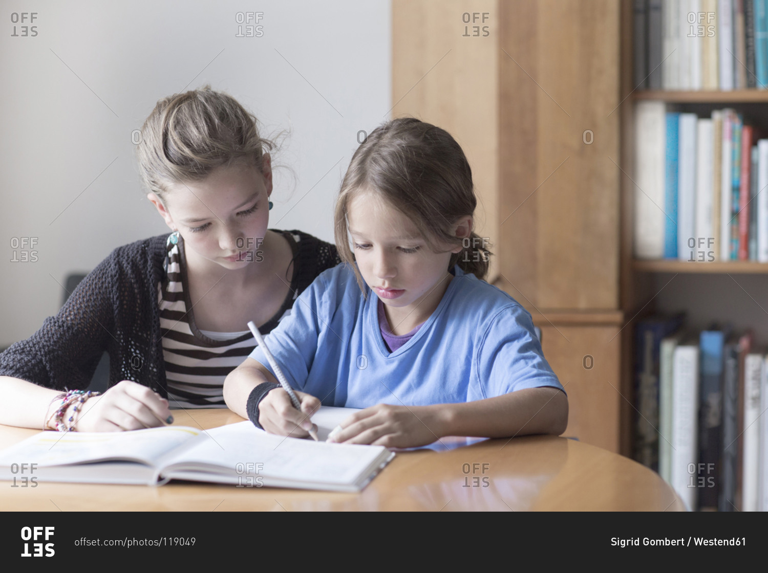Sister helping her little brother by doing his homework