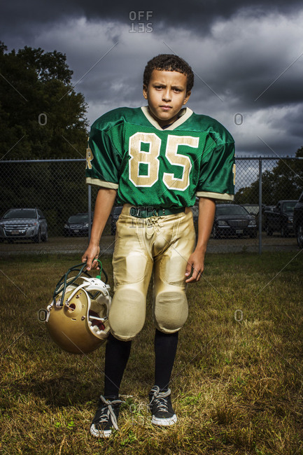 Young boy in football uniform holding helmet