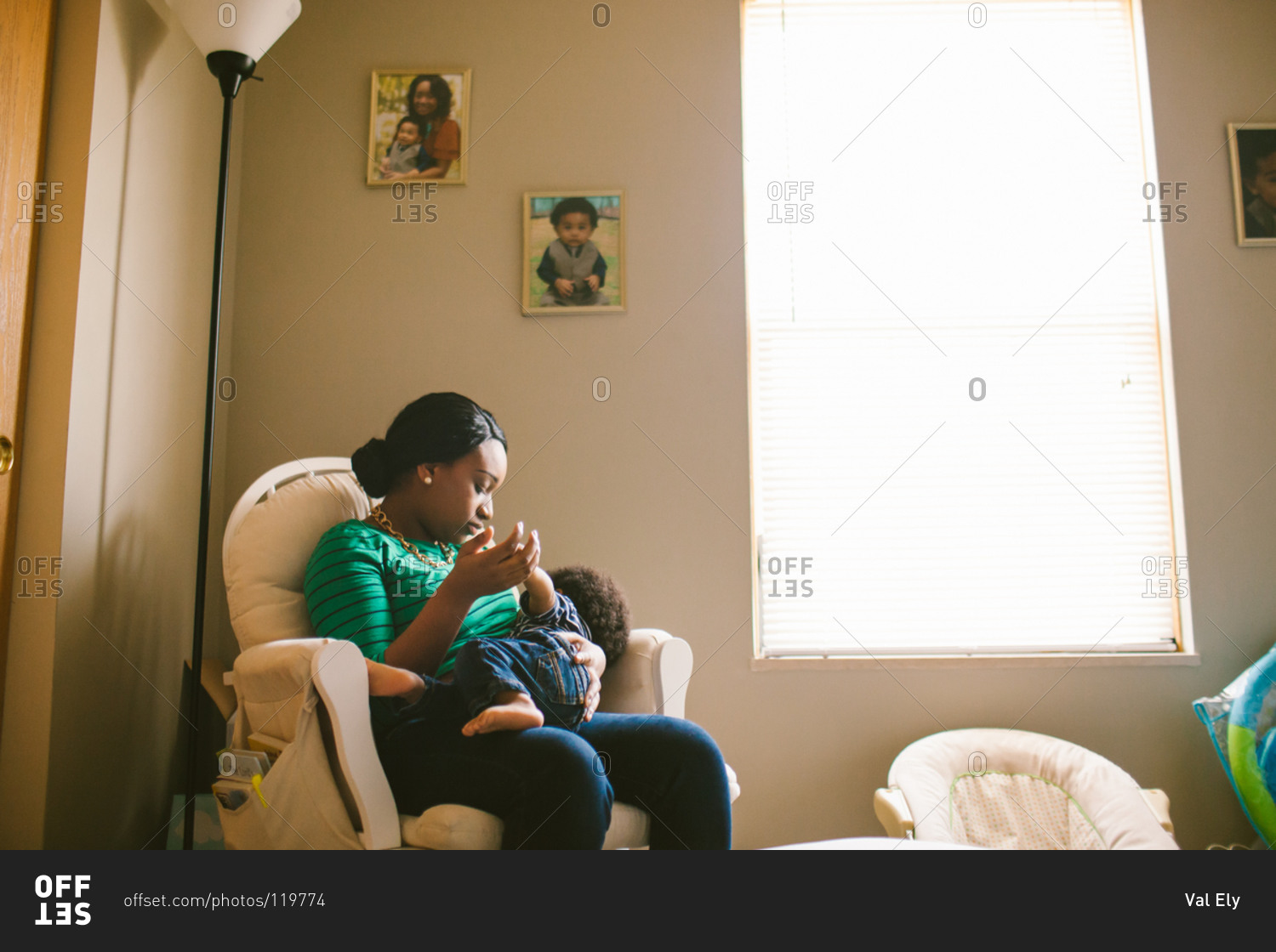 Mother breastfeeding her baby in nursery chair stock photo OFFSET