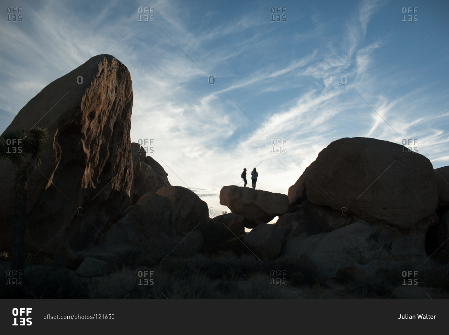 Women standing on a rock in the desert at sunset