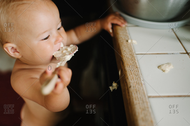 Child tasting food in a kitchen