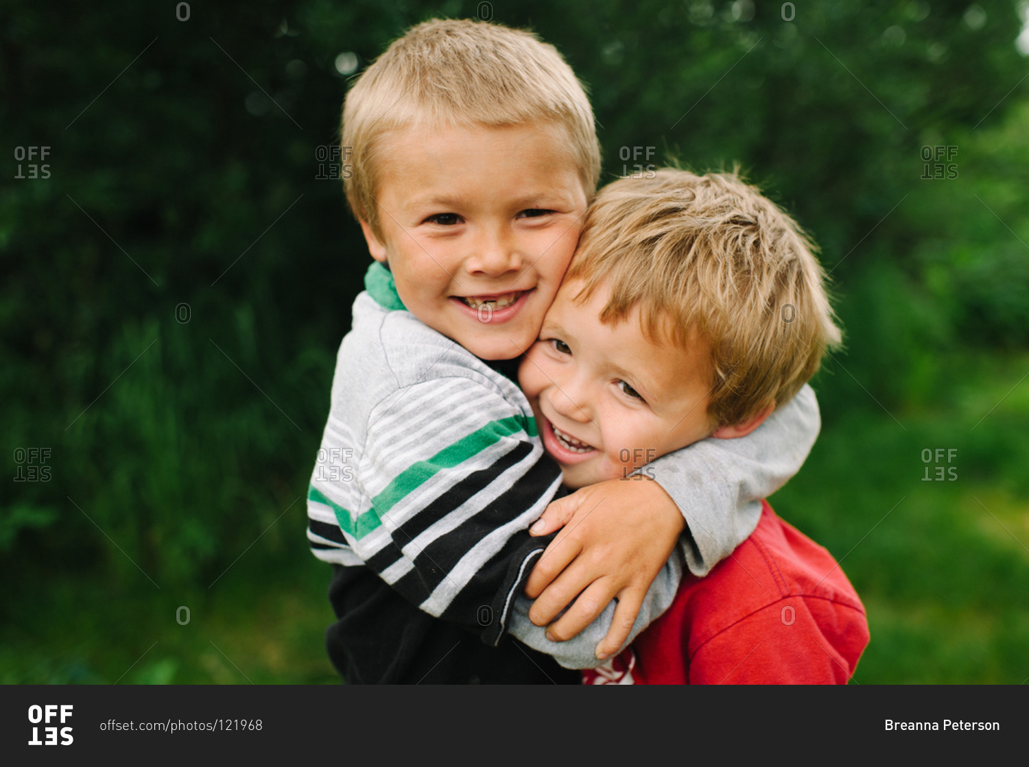 Older brother holding tight his younger brother stock photo - OFFSET