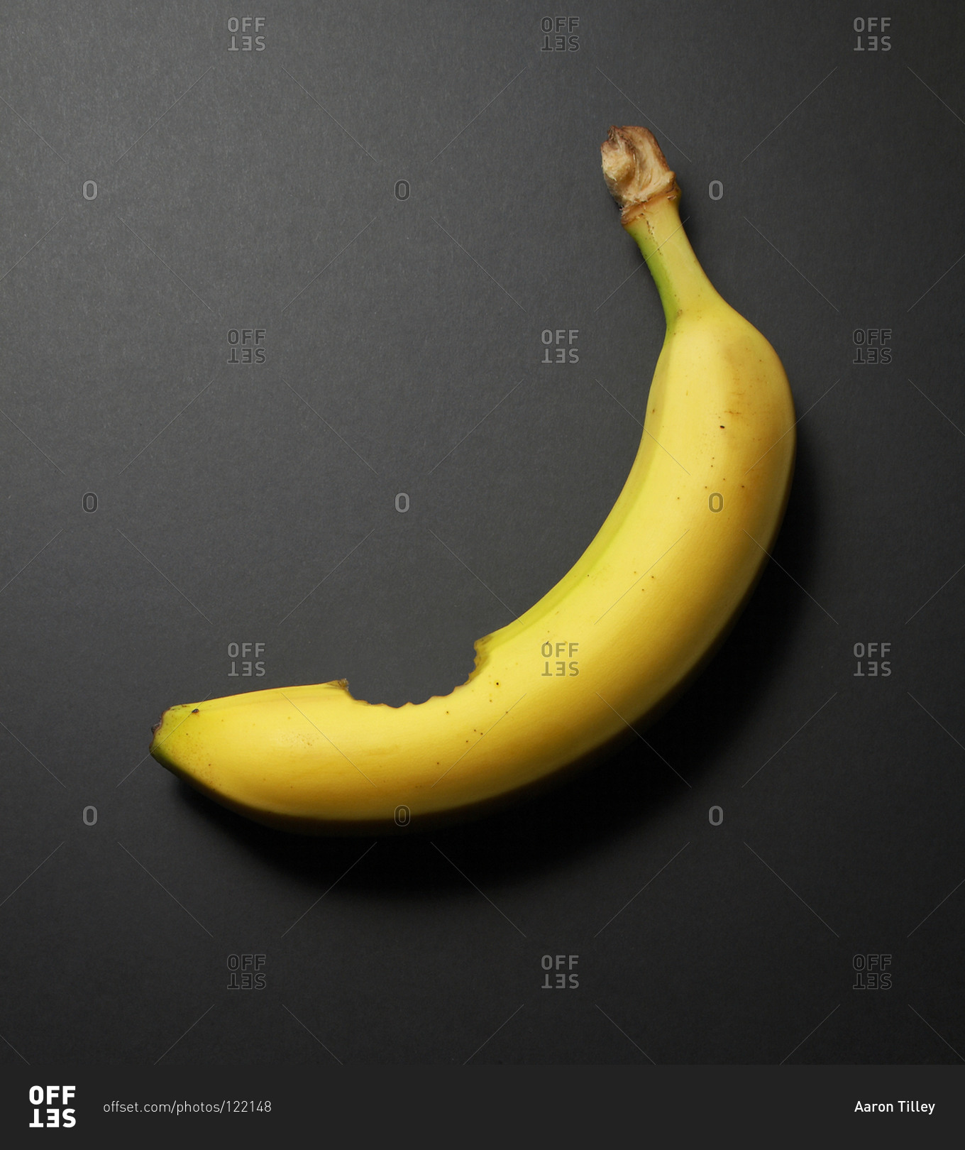 Studio shot of a banana with a bite stock photo - OFFSET