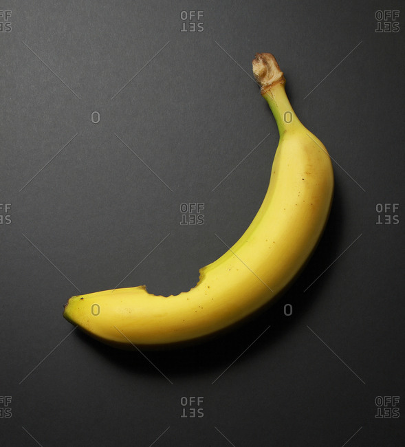 Studio shot of a banana with a bite stock photo - OFFSET