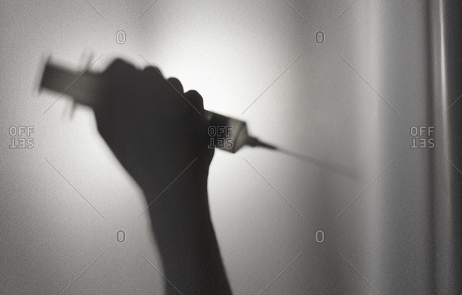 Silhouette of person holding a syringe