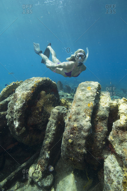 Female snorkeler dives down to view a winch on the Sugar wreck, West End, Grand Bahama Island