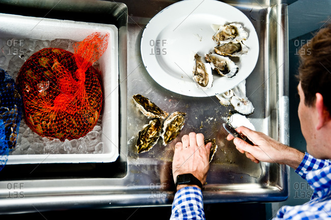 Overhead view of man halving oysters