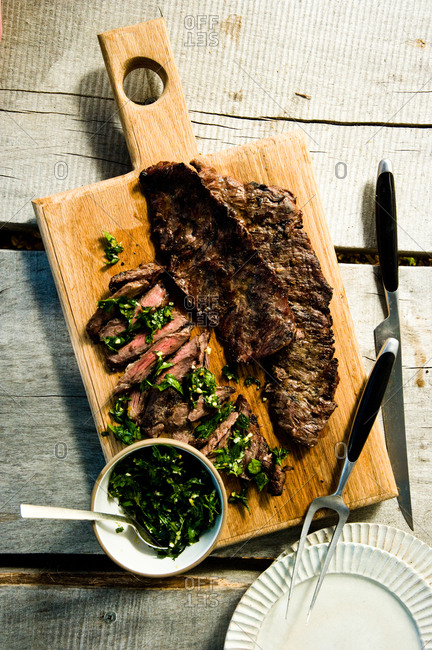 Grilled skirt steak with herb salsa verde on a cutting board