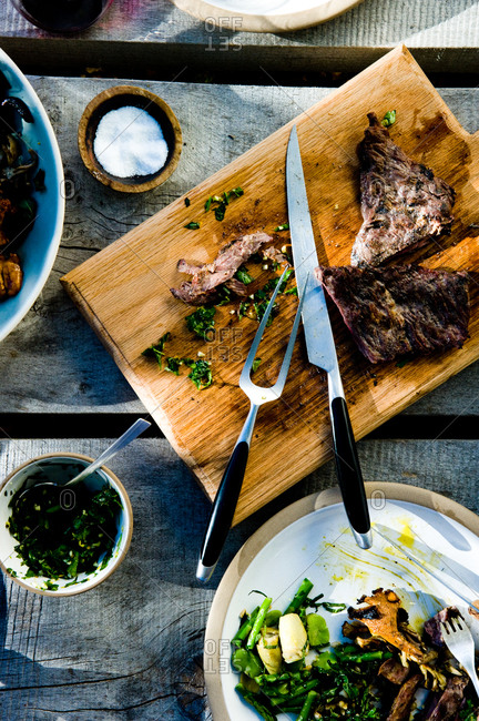 Sliced skirt steak with herb salsa verde on a cutting board