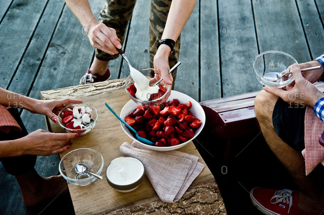 People serving fresh strawberries with chamomile cream