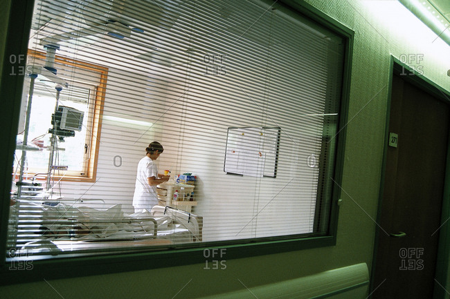 View of a nurse through the blinds of a hospital room