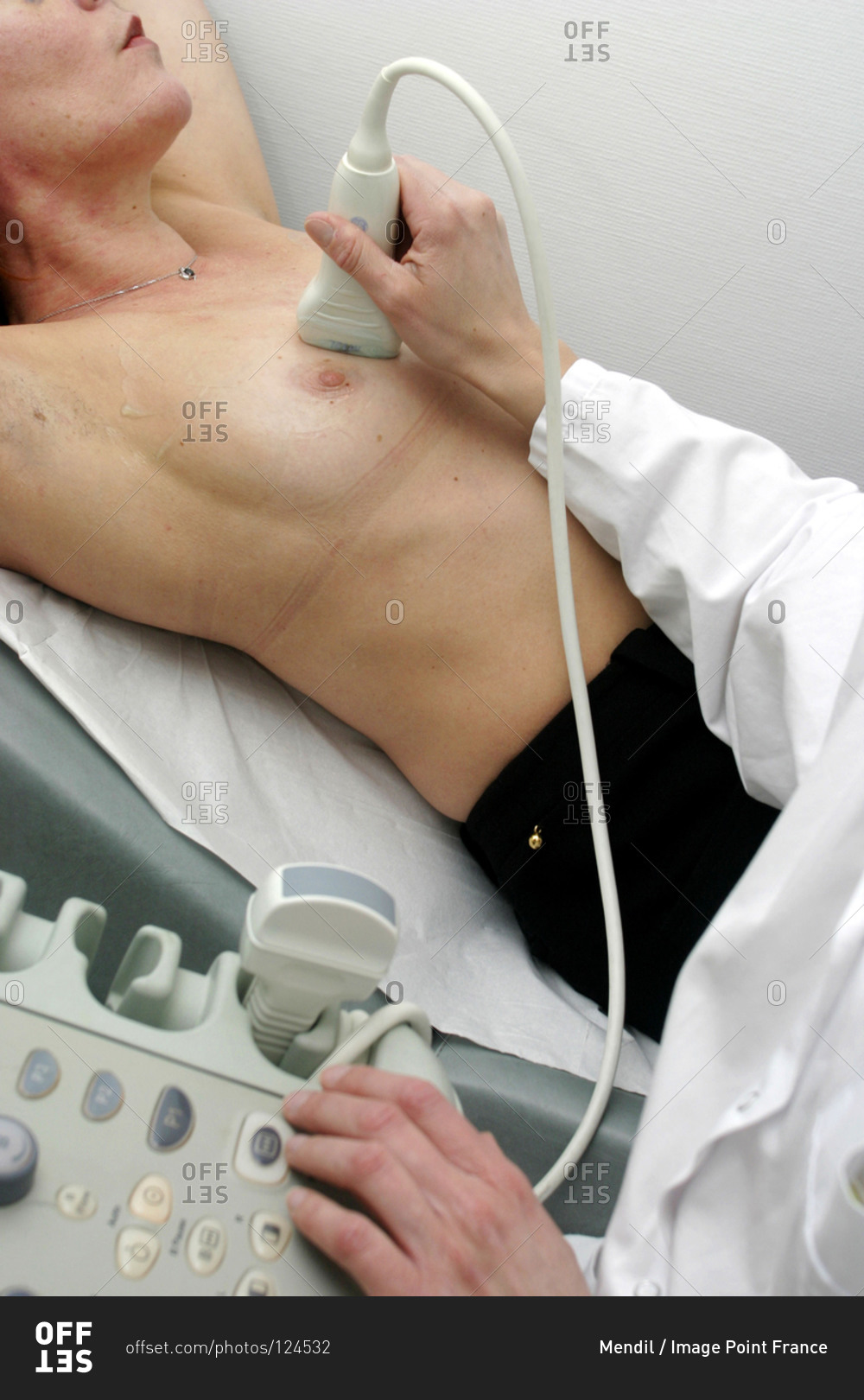 Woman undergoing a breast ultrasound examination in radiology room.