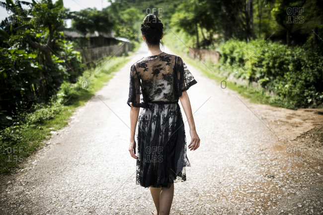 Woman in a black lace dress walking down a rural country road in northern Vietnam