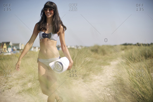 Young woman walking with folded beach towel