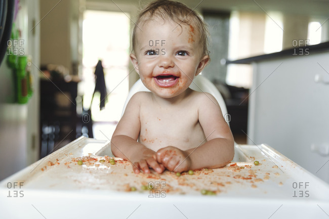 Smiling baby making mess on tray of highchair